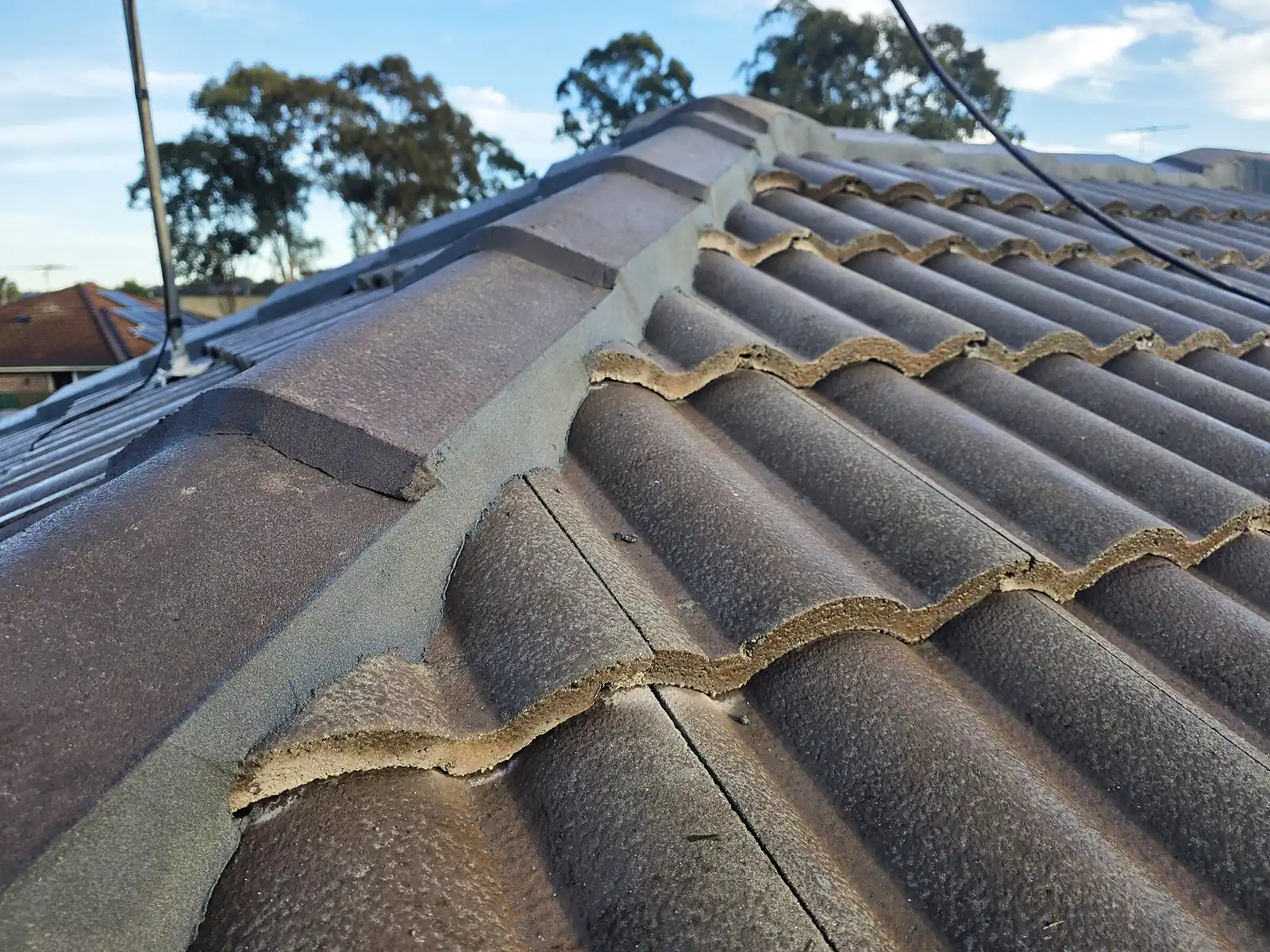 Ridge capping being rebedded on a concrete tile roof