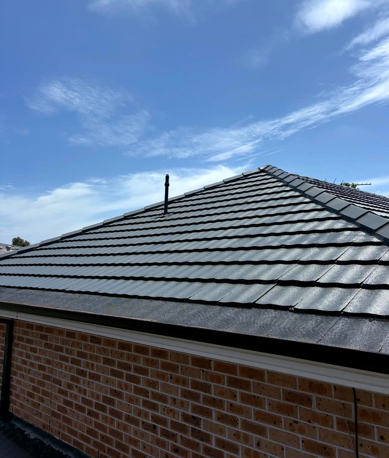 Tile roof restoration with fresh charcoal coating