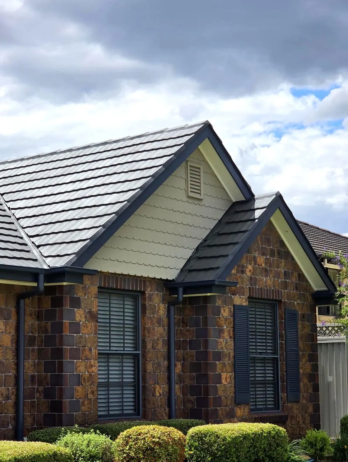 Brick home with a fully restored grey tile roof and trimmed gardens